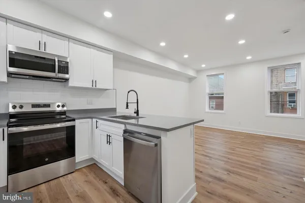 a kitchen with stainless steel appliances granite countertop a stove a sink and a microwave