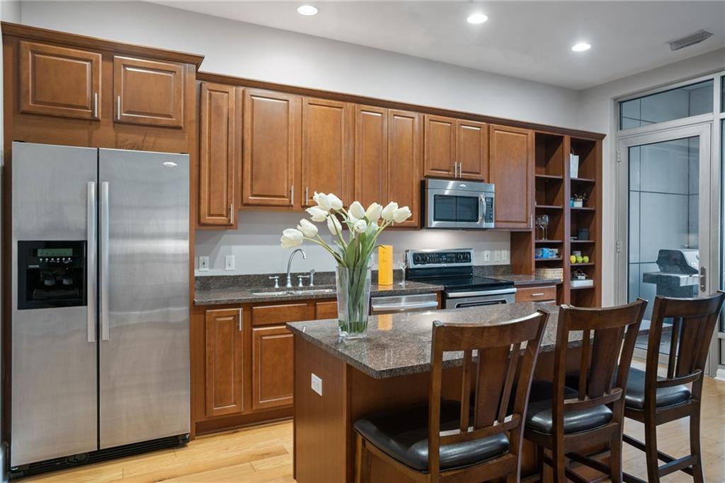 301 Fifth Avenue, Unit 511 Pittsburgh, PA 15222 - Photo 11 of 33 a kitchen with stainless steel appliances granite countertop a refrigerator a stove a sink a dining table and chairs