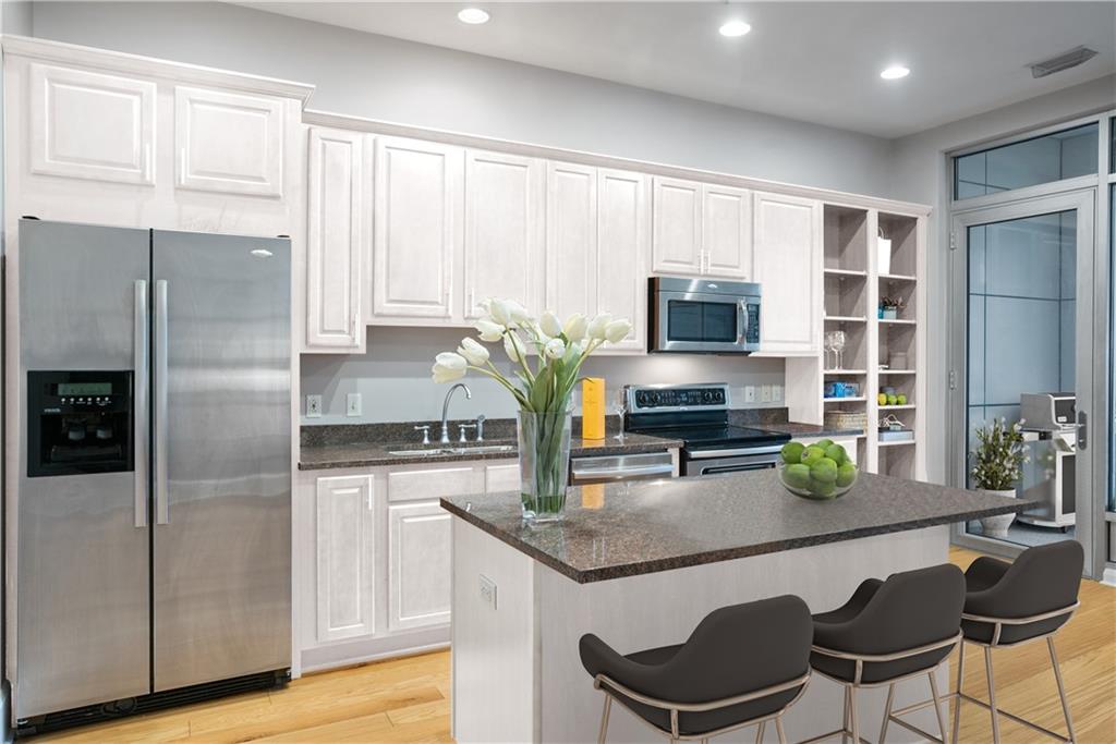 301 Fifth Avenue, Unit 511 Pittsburgh, PA 15222 - Photo 12 of 33 a kitchen with granite countertop a refrigerator a stove a sink cabinets and a dining table with chairs