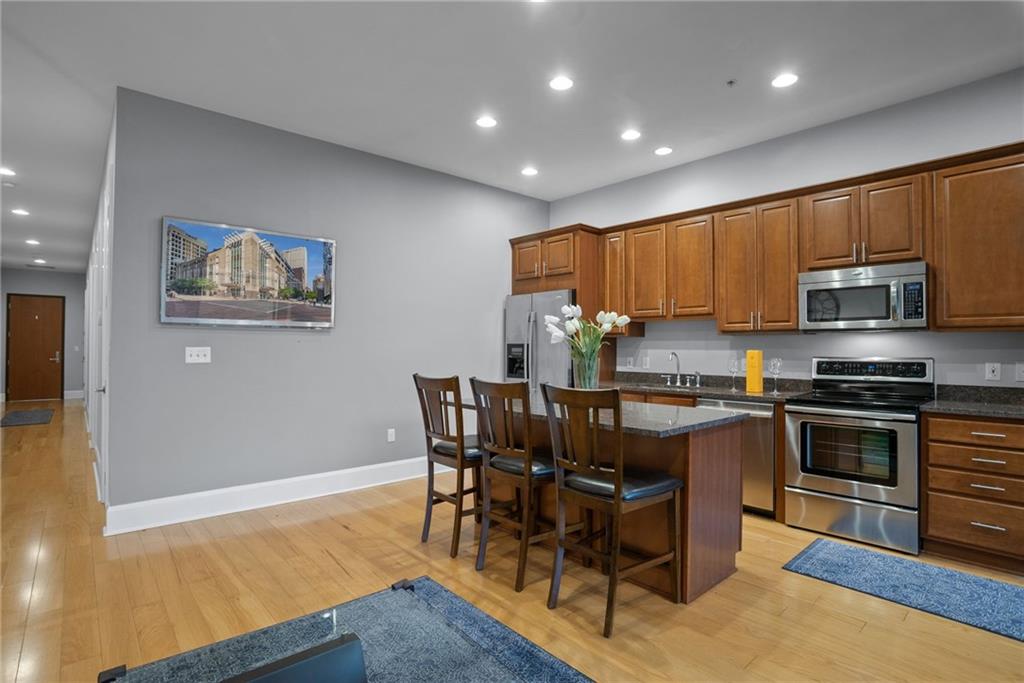 301 Fifth Avenue, Unit 511 Pittsburgh, PA 15222 - Photo 9 of 33 a kitchen with stainless steel appliances granite countertop a stove top oven a sink a dining table and chairs with wooden floor