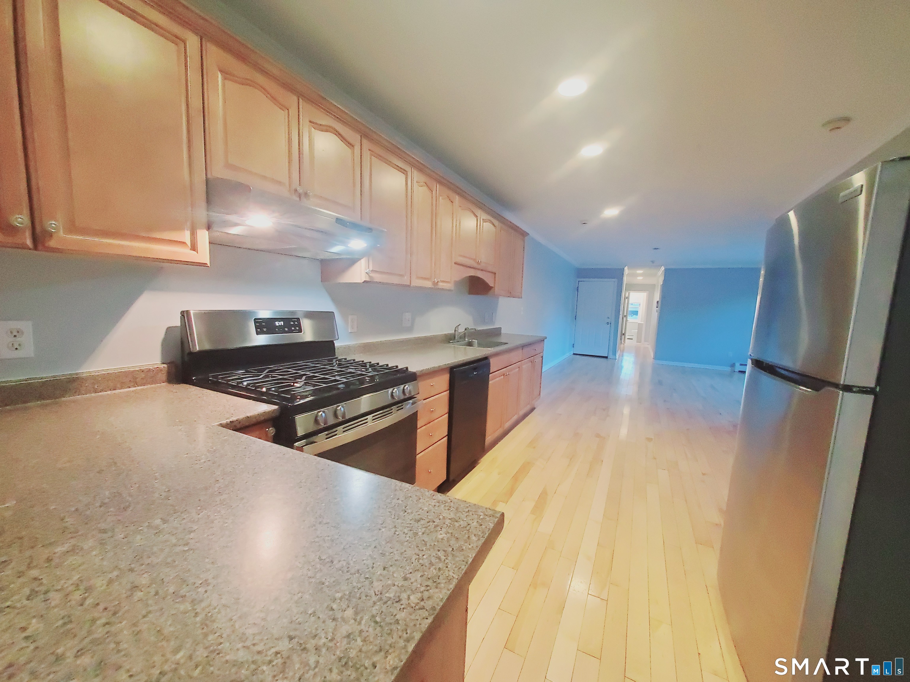 a kitchen with stainless steel appliances granite countertop a refrigerator a stove and a wooden floors