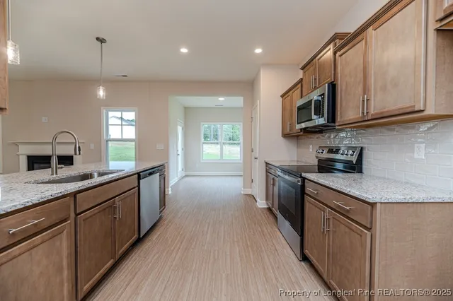 a kitchen with stainless steel appliances granite countertop wooden cabinets a sink dishwasher a stove and a refrigerator