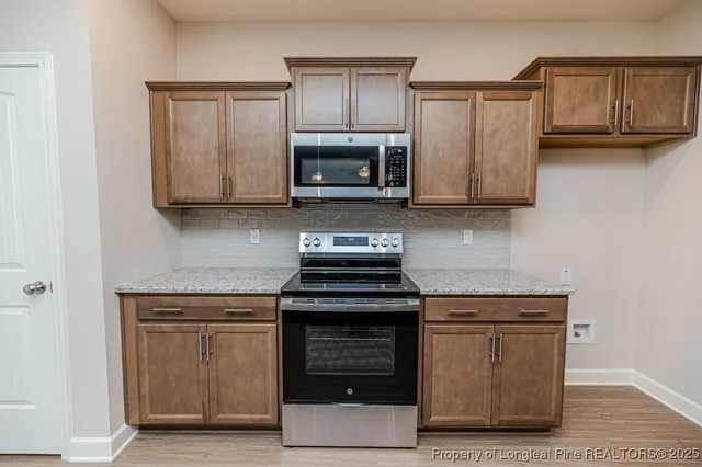 a kitchen with granite countertop wood cabinets and a stove top oven