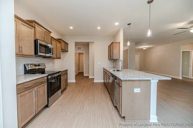 a kitchen with stainless steel appliances granite countertop wooden cabinets a sink dishwasher a stove and a refrigerator