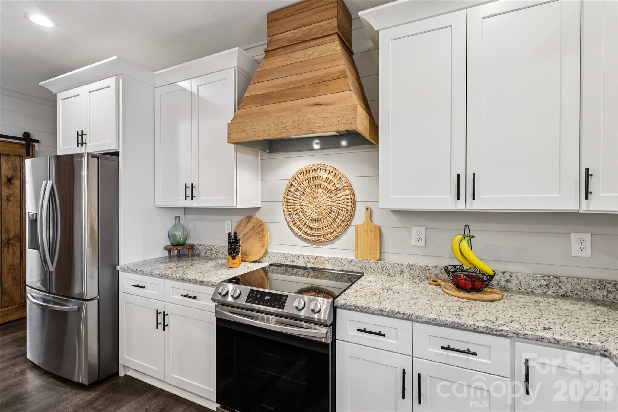 2807 Noritake Trail Albemarle, NC 28001 - Photo 20 of 45 a kitchen with stainless steel appliances granite countertop a stove a refrigerator and a white cabinets with wooden floor