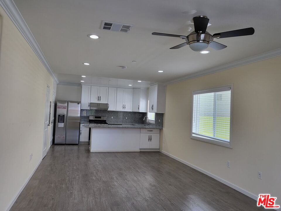 a living room with stainless steel appliances kitchen island hardwood floor and a window