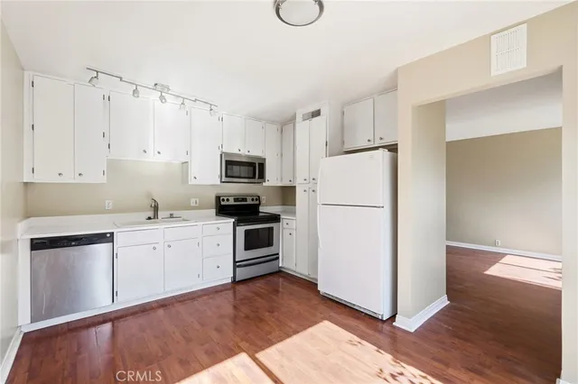 a kitchen with cabinets stainless steel appliances and wooden floor