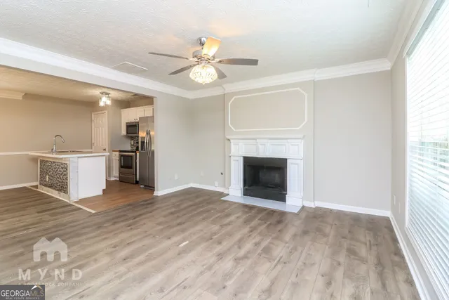 a view of a livingroom with a fireplace a ceiling fan and wooden floor