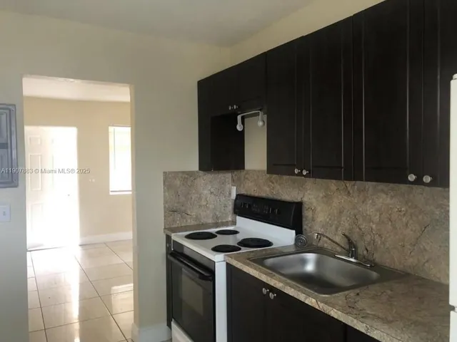 a kitchen with granite countertop a sink stove and cabinets