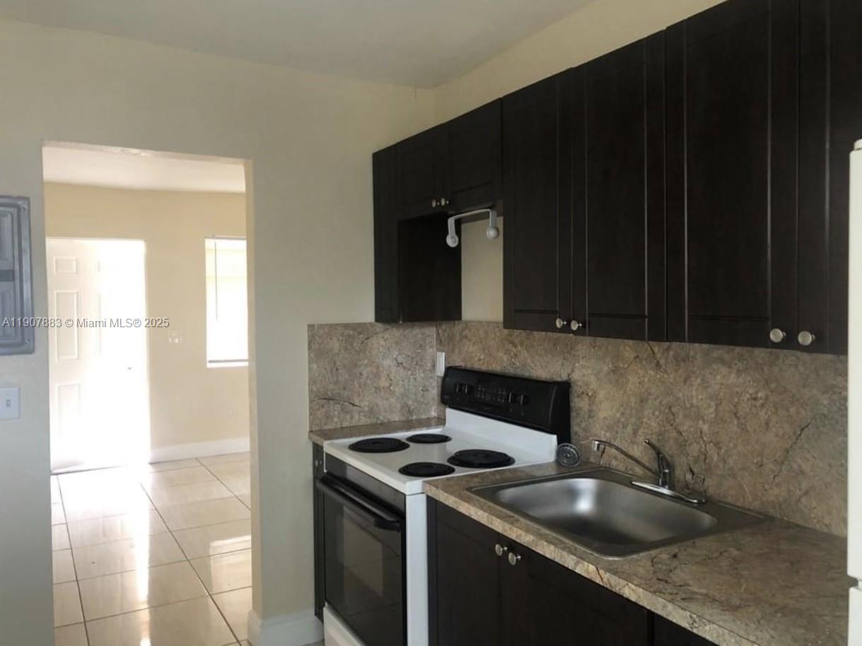 1940 Washington Avenue, Unit 15 Opa-Locka, FL 33054 - Photo 3 of 17 a kitchen with granite countertop a sink stove and cabinets