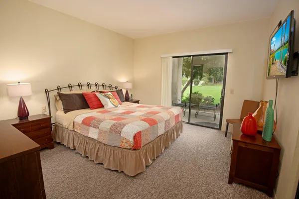 a spacious bedroom with a bed and a flat screen tv