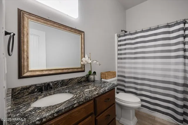 a bathroom with a granite countertop sink toilet and mirror