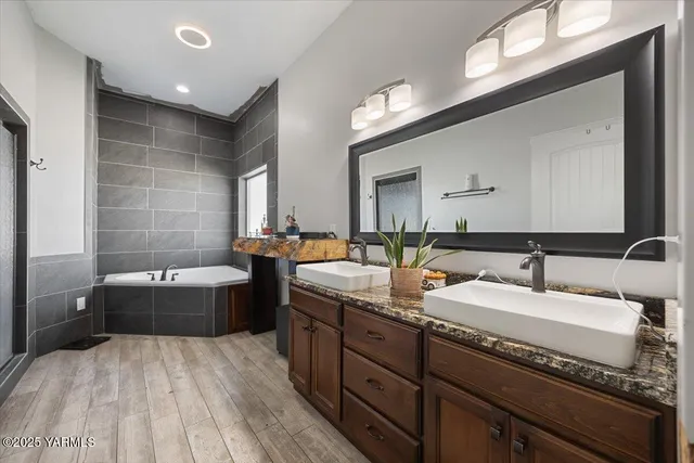 a bathroom with a tub double vanity sink and mirror