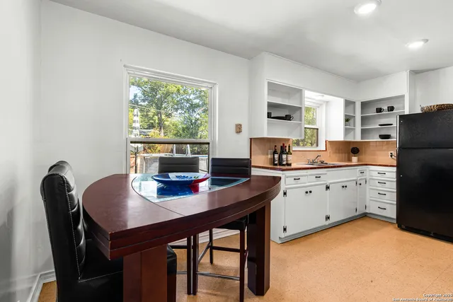 a kitchen with granite countertop a table chairs a refrigerator and a stove top oven