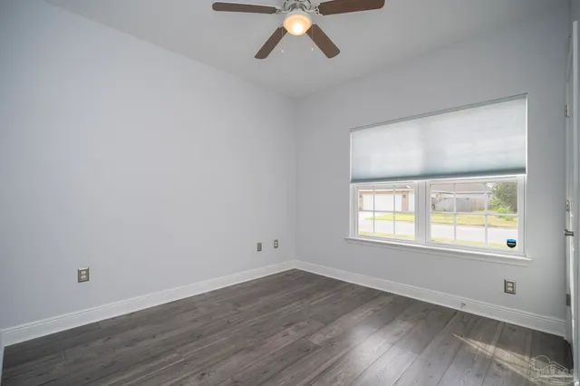 an empty room with wooden floor windows and ceiling fan