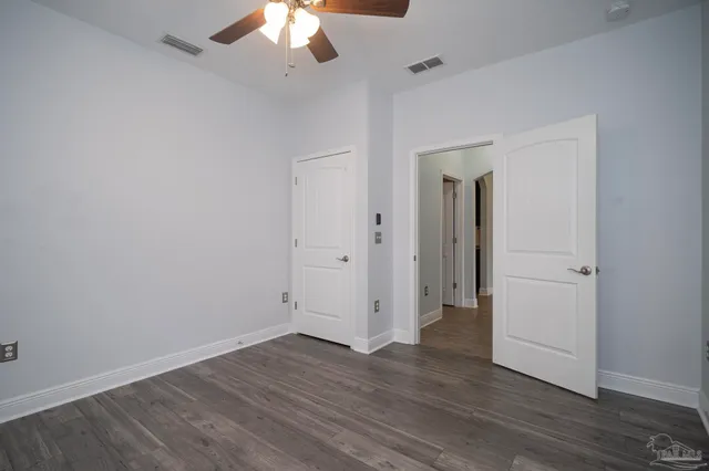 an empty room with wooden floor and ceiling fan