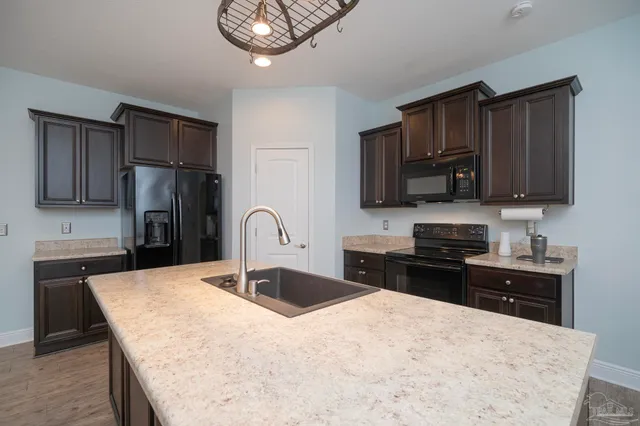 a kitchen with stainless steel appliances kitchen island a refrigerator sink and wooden cabinets