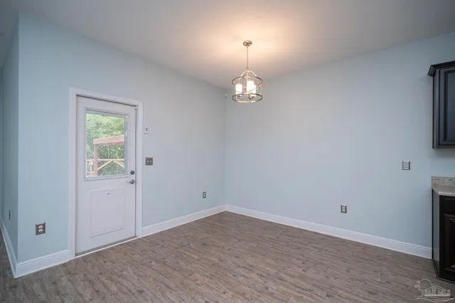 an empty room with wooden floor mirror and window