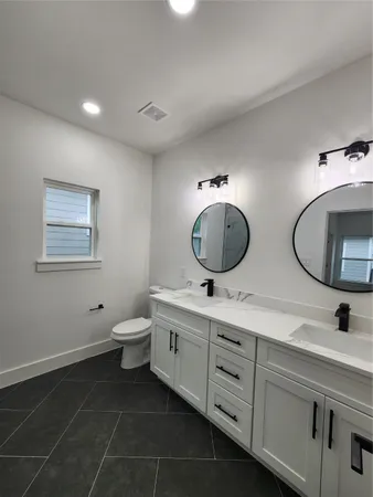 a bathroom with a double vanity sink mirror and toilet