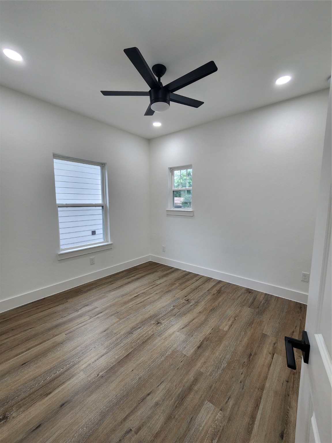 650 Everett Street, Unit B Conroe, TX 77301 - Photo 16 of 20 an empty room with wooden floor a ceiling fan and windows