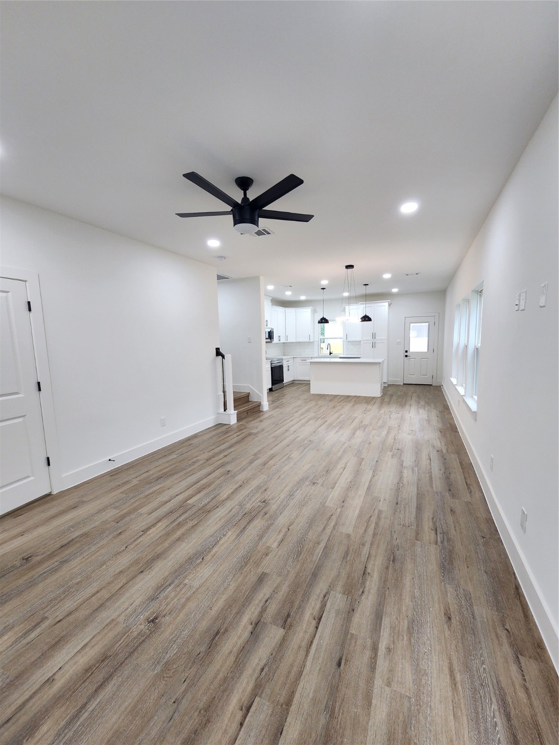 650 Everett Street, Unit B Conroe, TX 77301 - Photo 3 of 20 a view of a big room with wooden floor a ceiling fan and windows