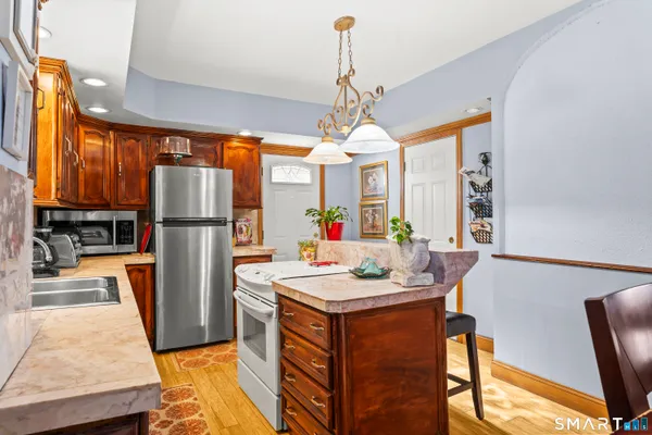 a kitchen with stainless steel appliances granite countertop a refrigerator a sink a stove and a refrigerator