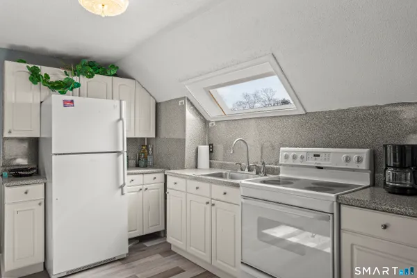 a kitchen with a sink a refrigerator a stove and white cabinets