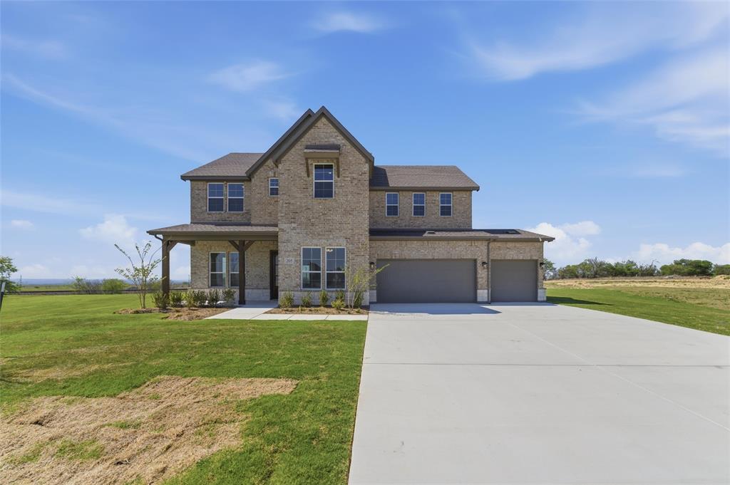 View of front of property with brick siding, a front lawn, covered porch, concrete driveway, and an attached garage