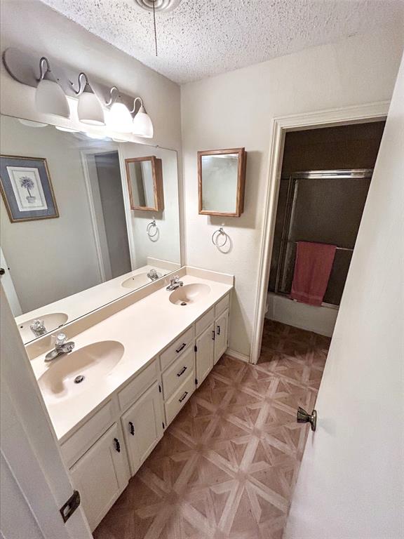 4905 Rippy Road Flower Mound, TX 75028 - Photo 12 of 29 Bathroom featuring a shower stall, double vanity, and a textured ceiling