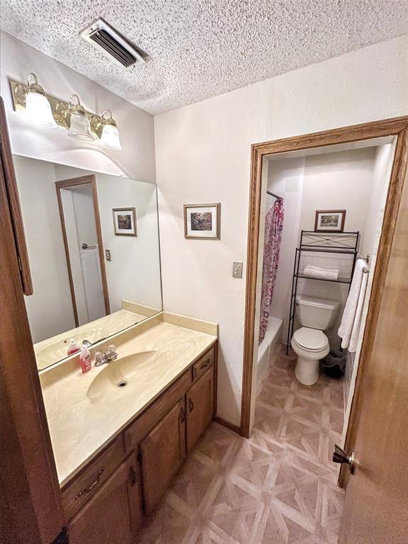 4905 Rippy Road Flower Mound, TX 75028 - Photo 20 of 29 Bathroom with toilet, vanity, a textured ceiling, and shower / bath combo