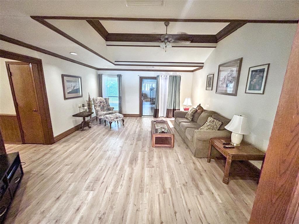 4905 Rippy Road Flower Mound, TX 75028 - Photo 8 of 29 Living room featuring crown molding, light wood-style flooring, baseboards, and beam ceiling