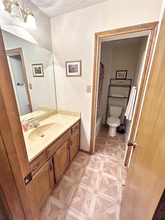 4905 Rippy Road Flower Mound, TX 75028 - Photo 10 of 29 Bathroom with vanity, a textured ceiling, toilet, and shower / bath combo with shower curtain