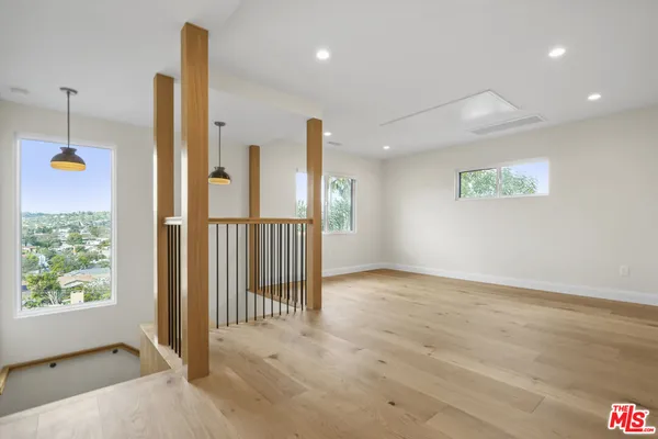 an empty room with wooden floor chandelier and windows