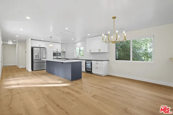 a view of kitchen with kitchen island stainless steel appliances sink cabinets and wooden floor