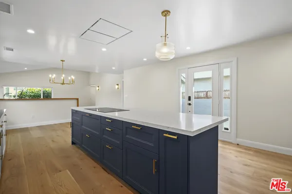 a kitchen with a sink chandelier and wooden floor