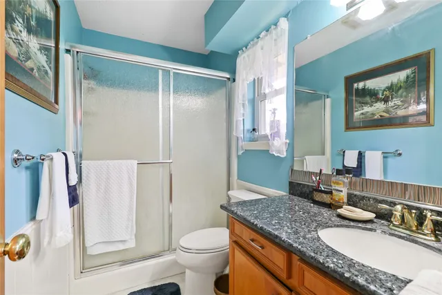 a bathroom with a granite countertop sink a toilet and a large mirror