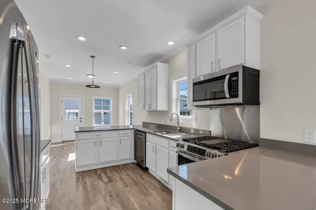 a large kitchen with stainless steel appliances granite countertop a stove a sink and a microwave