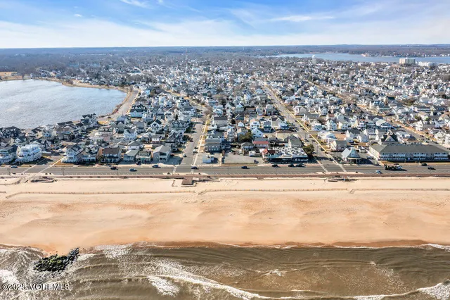 an aerial view of ocean and residential houses with outdoor space