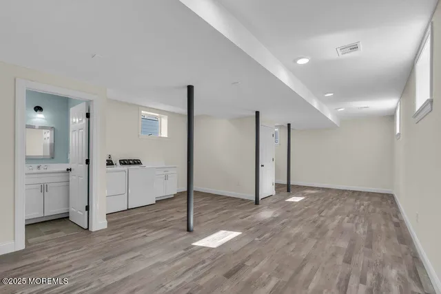a view of an empty room with wooden floor and a kitchen