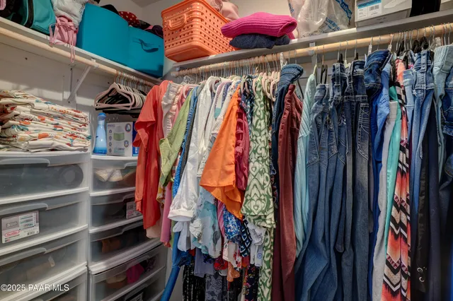 a view of walk in closet with clothes and shoes