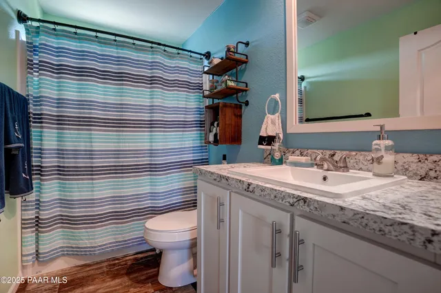 a bathroom with a granite countertop toilet a sink and mirror