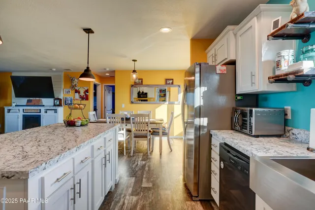 a kitchen with stainless steel appliances granite countertop a sink a stove and a wooden floor