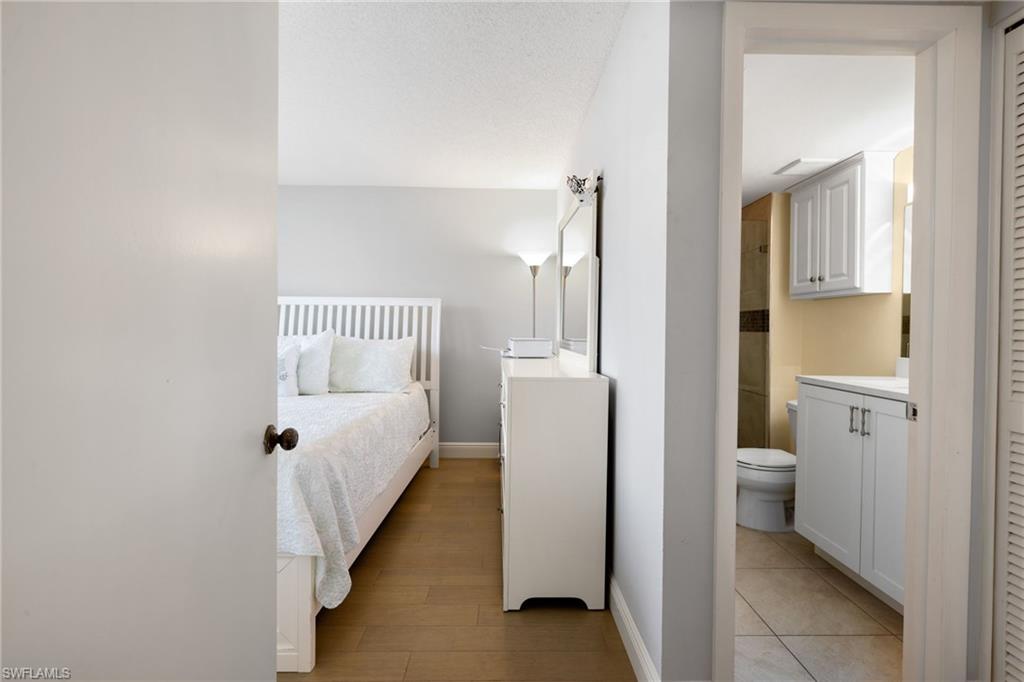 5 High Point Circle West, Unit 307 Naples, FL 34103 - Photo 14 of 31 Bedroom featuring connected bathroom and light wood-style floors