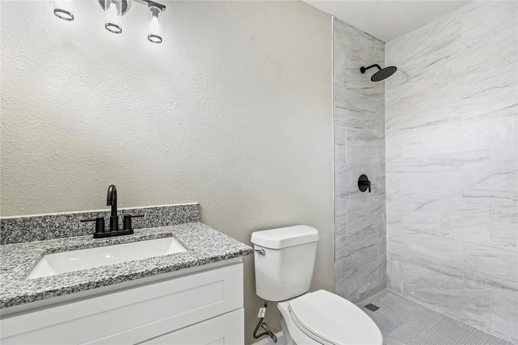 2116 Ridgeway Street Arlington, TX 76010 - Photo 16 of 21 a bathroom with a granite countertop sink a toilet and shower