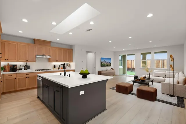 a large white kitchen with a large counter top a sink a window and living room