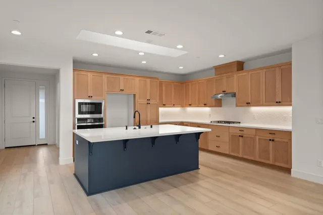 a large kitchen with cabinets a sink dishwasher and a stove with wooden floor