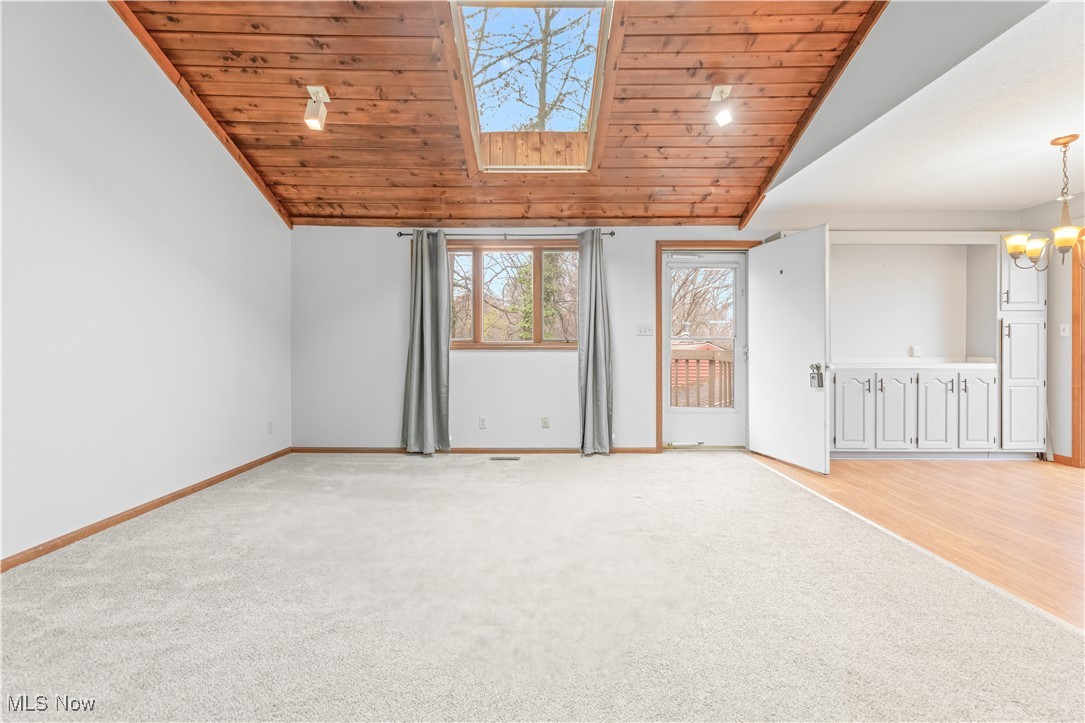 1574 Faye Road Akron, OH 44306 - Photo 7 of 45 Unfurnished living room featuring light colored carpet, wood ceiling, lofted ceiling, and an inviting chandelier
