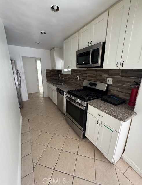7514 Beckford Avenue Reseda, CA 91335 - Photo 6 of 20 a kitchen with granite countertop a stove a microwave and a sink