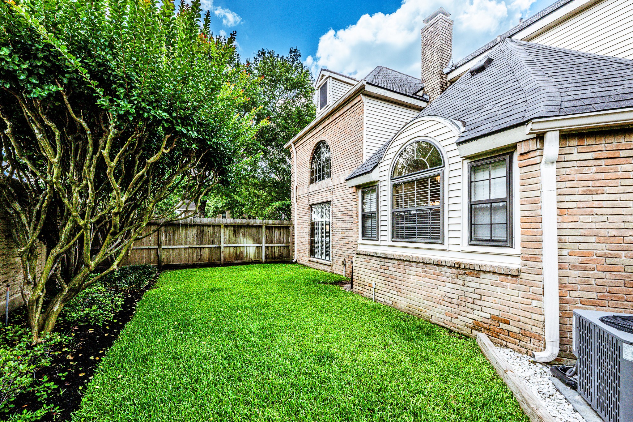 6047 Spring Creek Lane Spring, TX 77379 - Photo 45 of 50 A tucked away stretch of green space adds a rare sense of privacy while offering the perfect spot for pets to roam or quiet moments outdoors. Surrounded by mature landscaping and timeless brickwork, the area feels like a natural extension of the home’s relaxed outdoor setting.