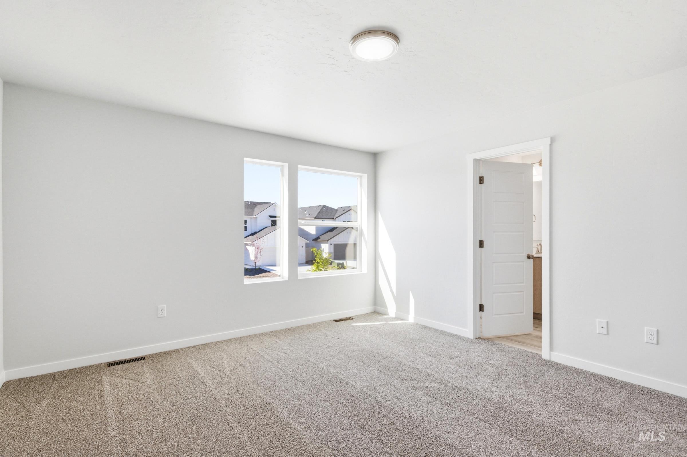 10812 Rutland Street Caldwell, ID 83605 - Photo 18 of 21 Carpeted room with white walls, two large rectangular windows, and a flush-mount ceiling light fixture